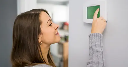 Woman adjusting thermostat